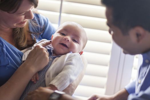 Happy Mixed Race Couple Enjoying Their Newborn Son In The Light of The Window.