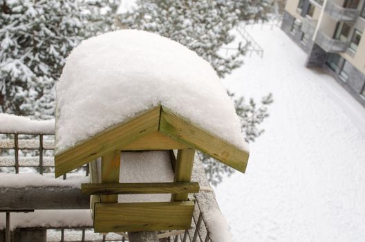 snow covered roof nesting-box on the balcony edge in cold winter time