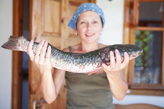 Nice mature woman with big fresh raw fish in her hand