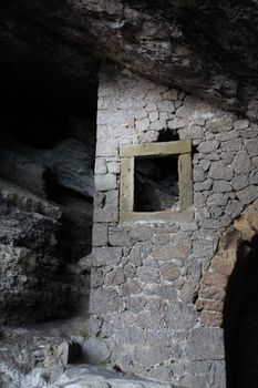 Fragment of the ancient stone wall with window in grotto