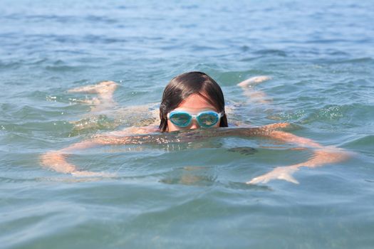 Closeup portrait of teenage girl with goggles swimming in sea