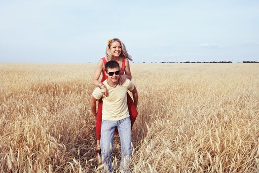 A man carries a girl in a wheat field