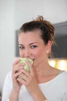 Portrait of a a pretty young woman drinking a mug of coffee indoors while taking a break