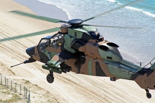 Australian Army Tiger reconnaissance chopper flies low over the coastline.