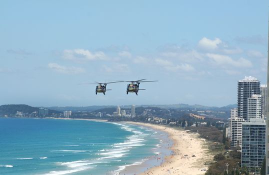 Australian Army Black choppers fly North across Surfers Paradise and Gold Coast beaches Australia.