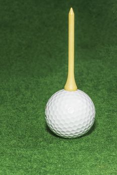 A golf tee sitting on top of a golf ball used for humor or to illustrate a concept.