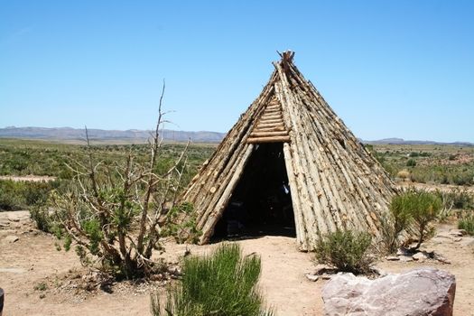 A native American Indian teepee made of wood sitting in the desert.