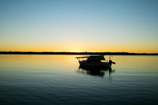 Lonely boat moored in a secluded bay just before dawn.