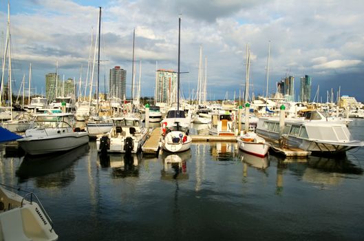 Busy marina boats framed against apartment towers with a dark sky.