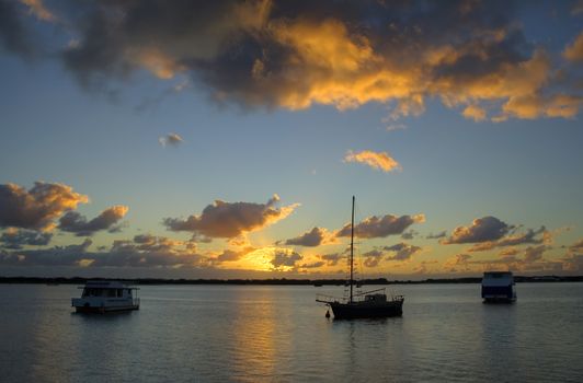 Sunrise breaks over yacht and boats in the still of the morning.