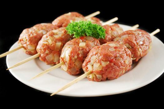 Raw beef koftas on skewers ready to cook.