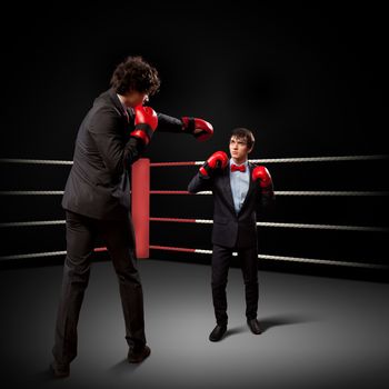 Two young businessman boxing againts dark background . conceptual collage