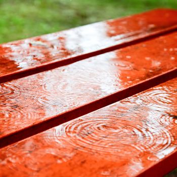 Rain drops rippling on a wet park bench
