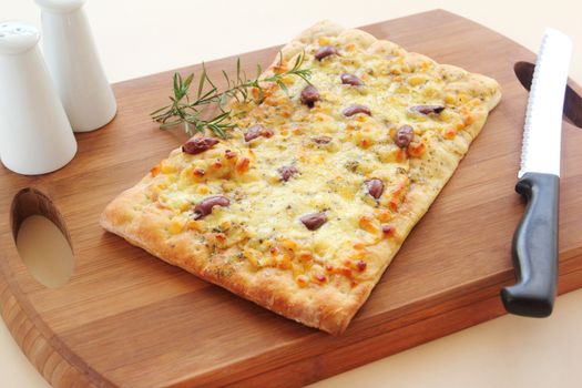 Rectangular gourmet pizza with cheese and olives ready to serve.