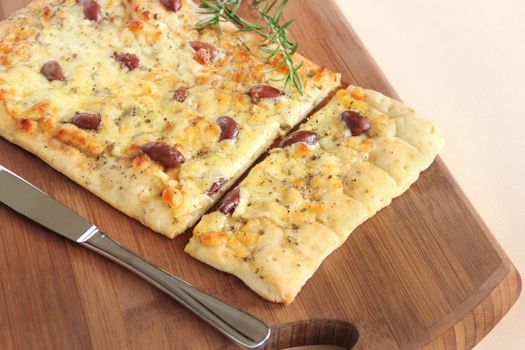 Rectangular gourmet pizza with cheese and olives ready to serve.