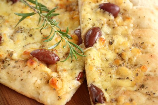 Sliced rectangular gourmet pizza with cheese and olives ready to serve.