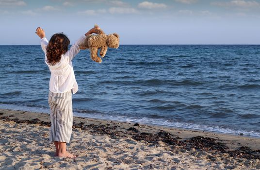happy little girl with teddy bear on beach