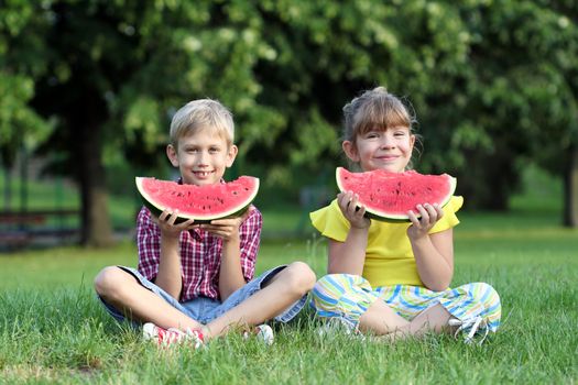 little girl and boy eat watermelon