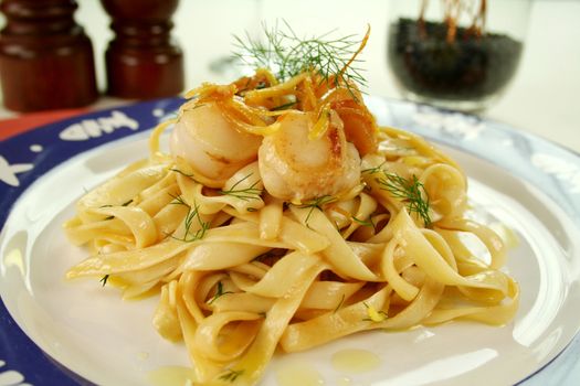 Fettucini with caramelized lemon and dill sea scallops in a table setting.