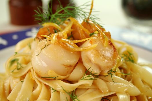 Fettucini with caramelized lemon and dill sea scallops in a table setting.