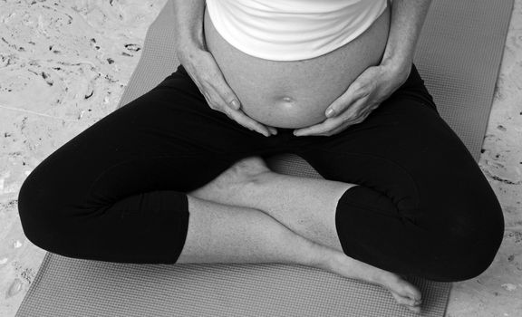 pregnant woman practicing prenatal yoga while holding belly