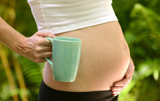 pregnant woman holding mug for concept of caffeine or coffee during pregnancy