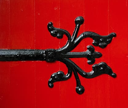 A Black Ornamental Hinge On Freshly Painted Red Door