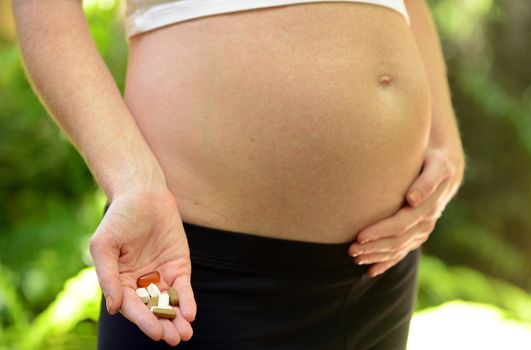 pregnant woman taking prenatal vitamins, fish oil and supplements during pregnancy