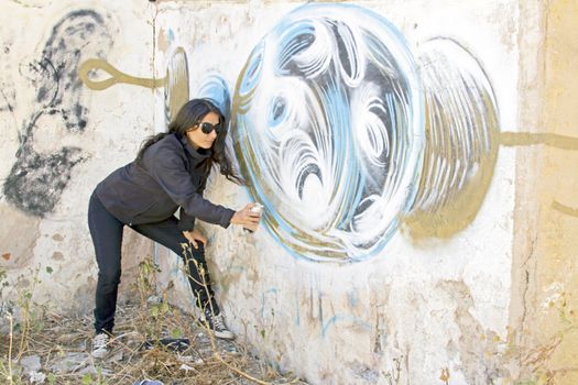 Woman spraying a graffiti wall