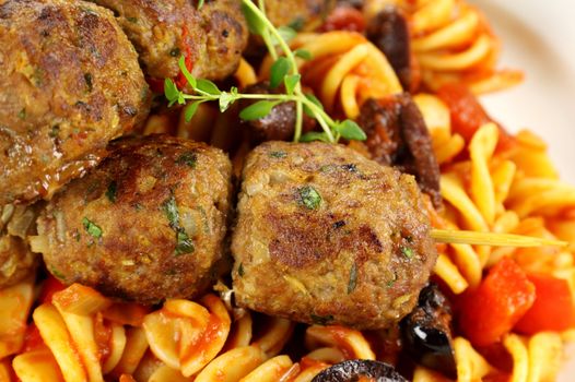 Delicious beef meatballs on tomato and olive pasta.