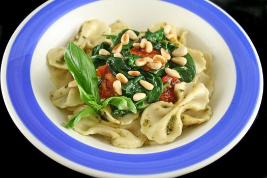 Pasta with pesto and spinach, cherry tomatoes and pine nuts.