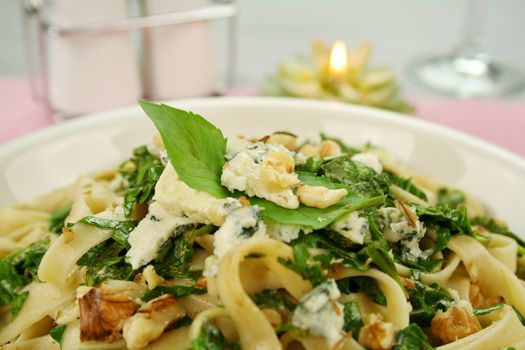 Fettucini with spinach blue cheese and walnuts with a basil garnish.