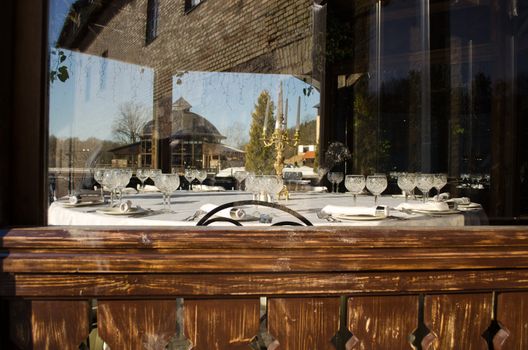 lay spread set table with glasses dishes candlestick under windows in park restaurant waiting for newlywed people.