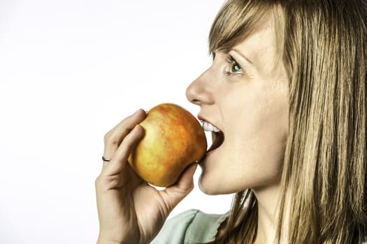 Portrait of a young girl biting into a red yellow apple, isolated on white background