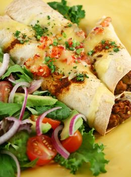 Beef and red kidney bean enchiladas with cheese and salad.