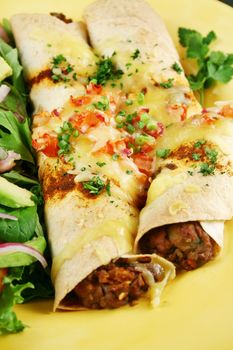 Beef and red kidney bean enchiladas with cheese and salad.
