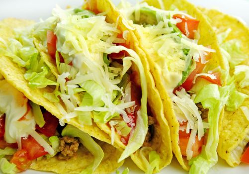 Delicious beef tacos with beef, lettuce, tomato salsa, avocado, grated cheese and sour cream.