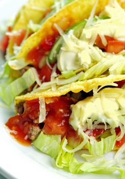 Delicious beef tacos with beef, lettuce, tomato salsa, avocado, grated cheese and sour cream.