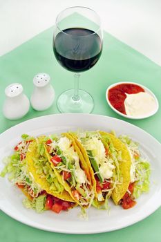 Delicious beef tacos with beef, lettuce, tomato salsa, avocado, grated cheese and sour cream.