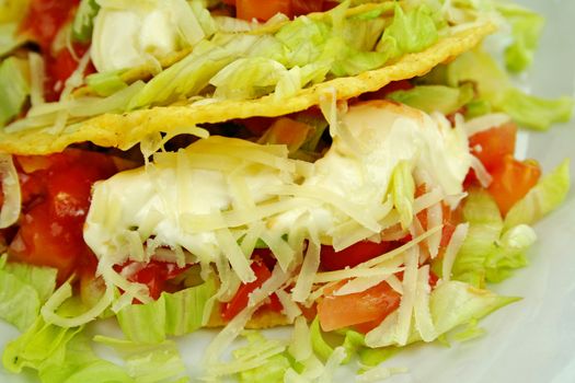 Delicious beef tacos with beef, lettuce, tomato salsa, avocado, grated cheese and sour cream.