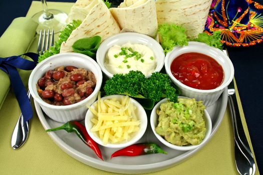 Mexican vegetarian platter with tortillas, guacamole, refried beans, cheese, sour cream and tomato salsa