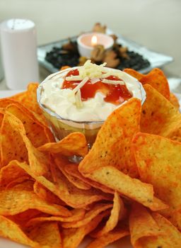 Nachos and Mexican dip topped with sour cream, salsa and grated cheese.