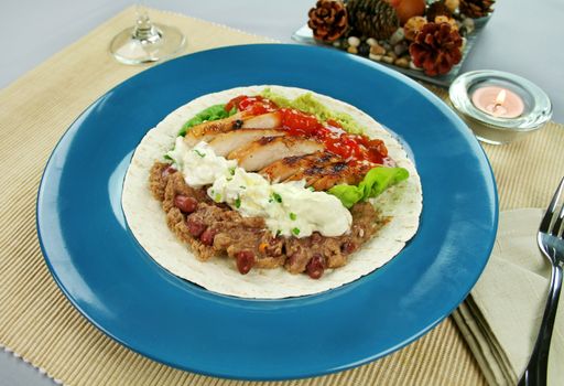 Open chicken tortilla with refried beans, guacamole and sour cream with chives.