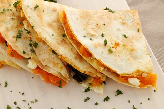 Delicious pumpkin quesadilla sliced and ready to serve with chopped parsley.