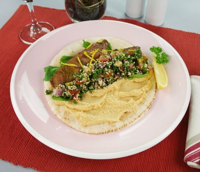 Middle Eastern lamb fillet on pita bread with hommus and tabouleh and lemon parsley.