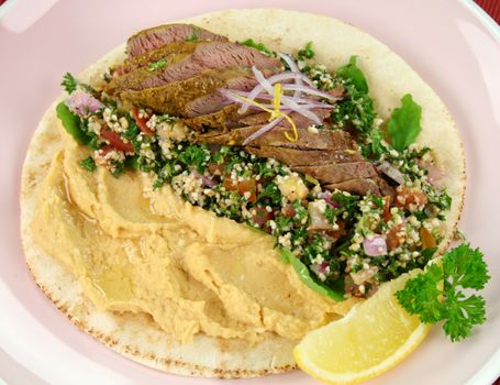 Middle Eastern lamb fillet on pita bread with hommus and tabouleh and lemon parsley.