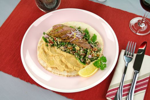 Middle Eastern lamb fillet on pita bread with hommus and tabouleh and lemon parsley.