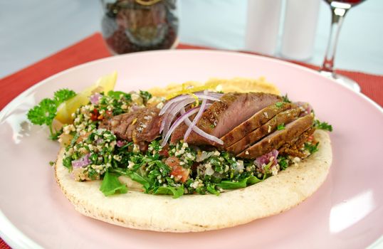 Middle Eastern lamb fillet on pita bread with hommus and tabouleh and lemon parsley.