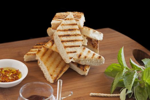 Grilled and toasted bread stack with condiments and herbs.