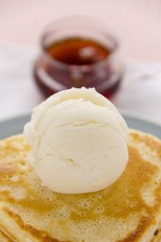 Scoop of vanilla ice cream on a pancake with maple syrup.